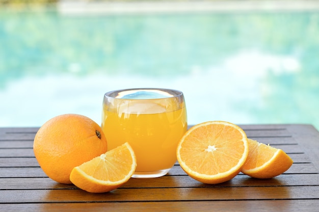Verre de jus d'orange frais avec des fruits frais sur table en bois