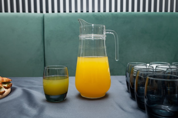 Verre de jus d'orange frais et grand pichet de boisson aux fruits.