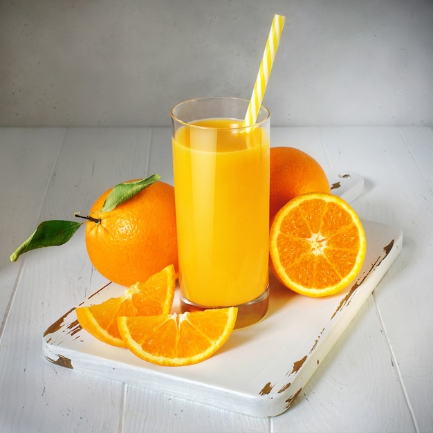 Verre de jus d'orange et de fruits frais sur une table en bois blanc, style vintage