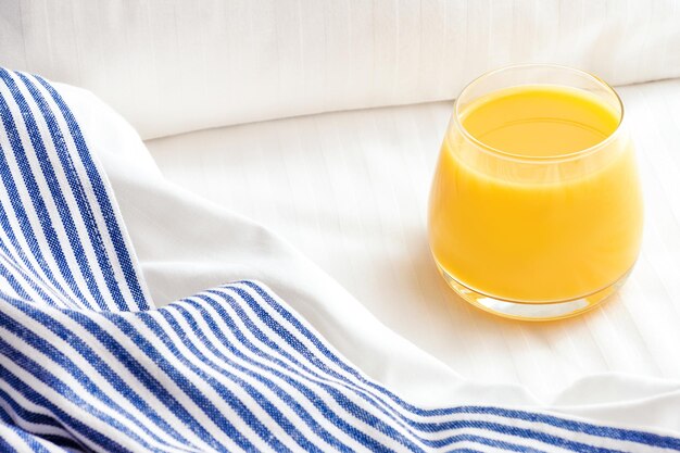 Verre de jus d'orange sur le lit avec couvre-lit