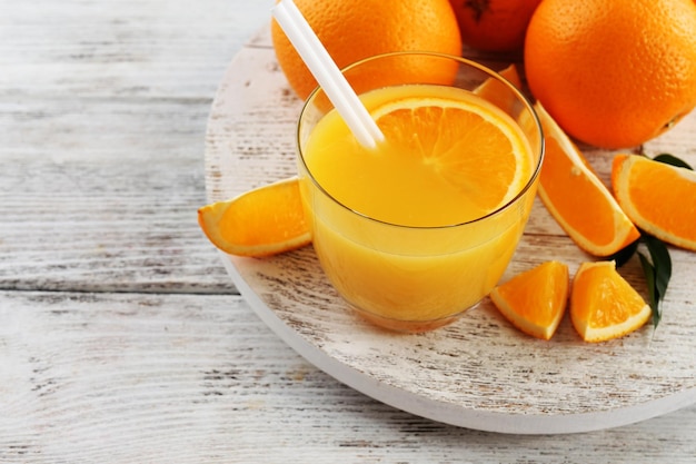 Verre de jus d'orange avec paille et tranches sur fond de table en bois