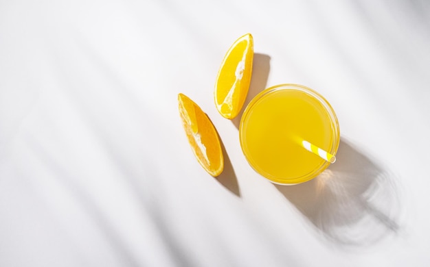 Un Verre De Jus D'orange Et Une Tranche D'orange Sur Une Table Lumineuse à L'ombre Des Feuilles De Palmier Heure D'été Vue De Dessus Et Espace De Copie