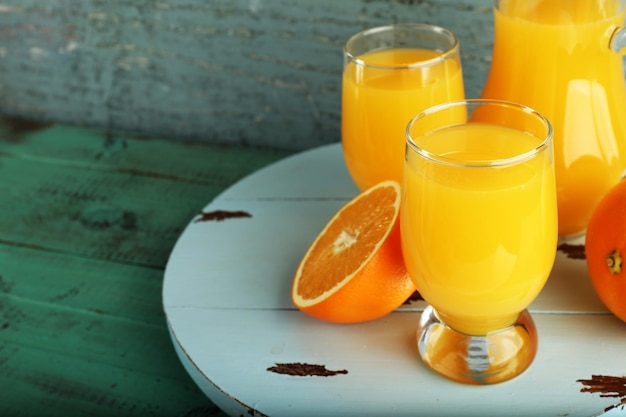 Verre de jus d'orange avec des tranches sur fond de bois de couleur