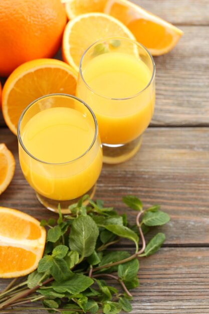 Photo verre de jus d'orange et tranches sur fond de table en bois