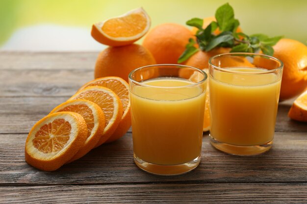 Verre de jus d'orange et tranches sur table en bois et fond clair
