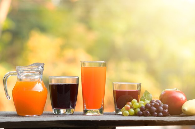 Verre de jus organique frais avec des fruits frais sur une table en bois sur fond de bokeh vert