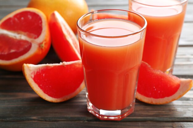 Verre de jus de pamplemousse et de fruits frais sur fond de bois