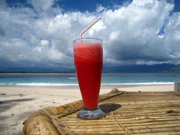 Verre de jus de pastèque devant la plage paradisiaque