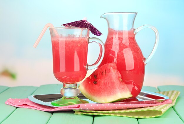 Verre de jus de pastèque frais sur table en bois sur fond clair