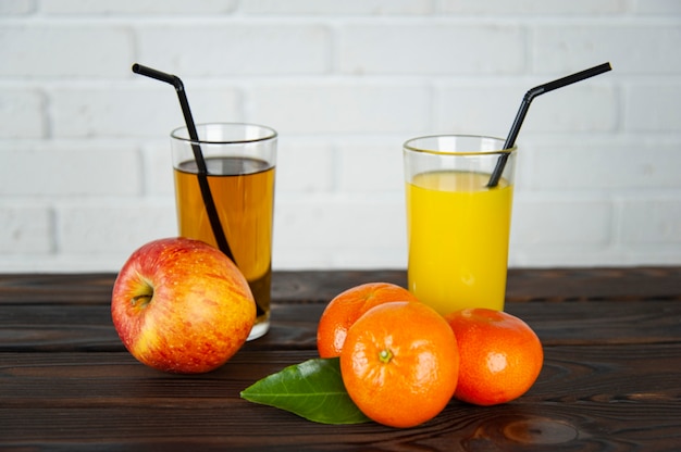 Verre de jus de pomme et d'orange avec des pommes et des oranges sur la table