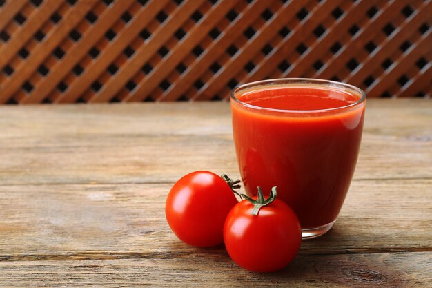 Un verre de jus de tomate frais sur fond de bois