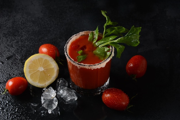 Verre de jus de tomate frais et tomates sur fond sombre avec des gouttes d'eau