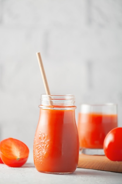 Verre de jus de tomate avec des légumes sur fond de mur de briques blanches