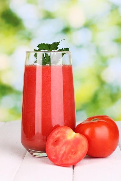 Verre de jus de tomate sur table en bois sur fond vert