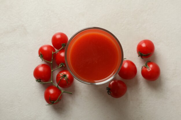 Verre de jus de tomate et tomates sur blanc texturé