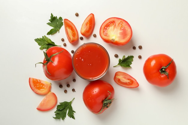 Verre de jus de tomate, tomates et épices sur fond blanc