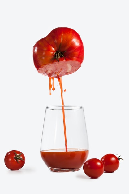 Verre de jus de tomate tourné de manière créative sur fond blanc