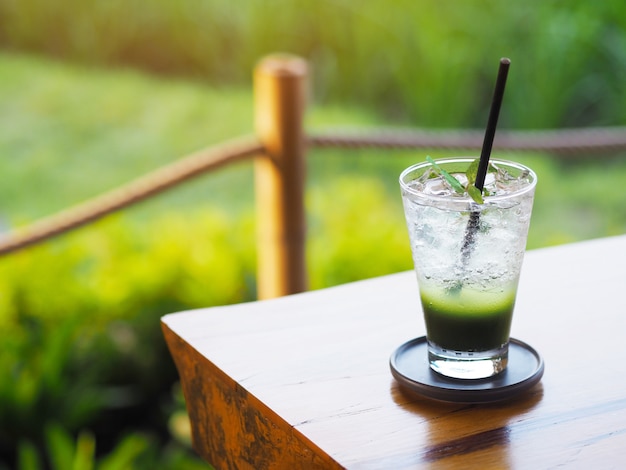 Verre de jus vert sur table en bois