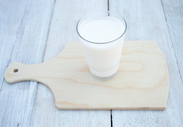 Photo verre de kéfir sur un support en bois sur un fond en bois blanc