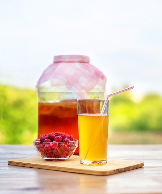 Un verre de kombucha sur fond de jardin d'été et de ciel