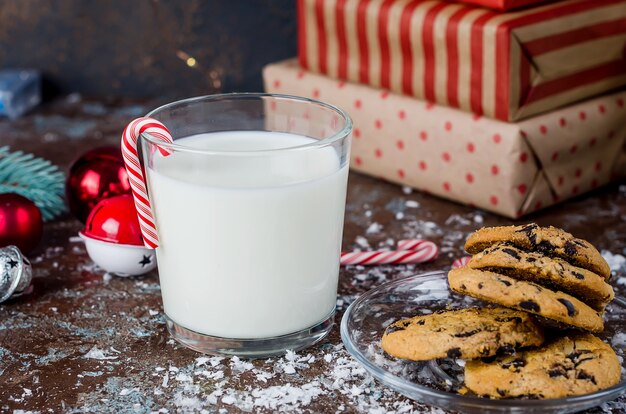 Verre de lait et biscuits maison au chocolat sur table, décorations de Noël,