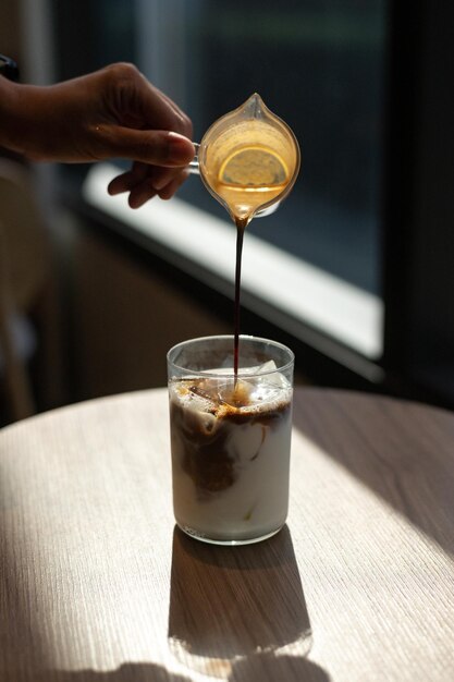 Un verre de lait avec une cuillère versant un cappuccino dedans.