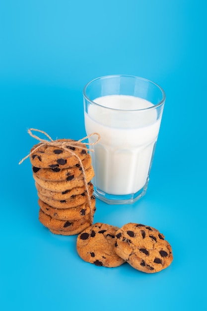 Verre de lait frais et biscuits au chokolate d'école brune sur fond bleu