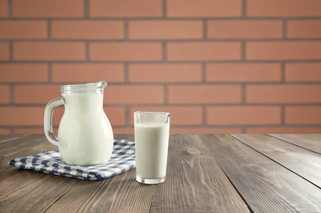 Photo verre de lait frais et pot sur une table en bois avec cuisine flou comme arrière-plan pour le produit de montage.
