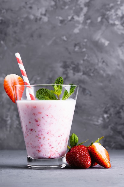 Verre de lait frappé aux fraises et à la menthe sur une surface en béton