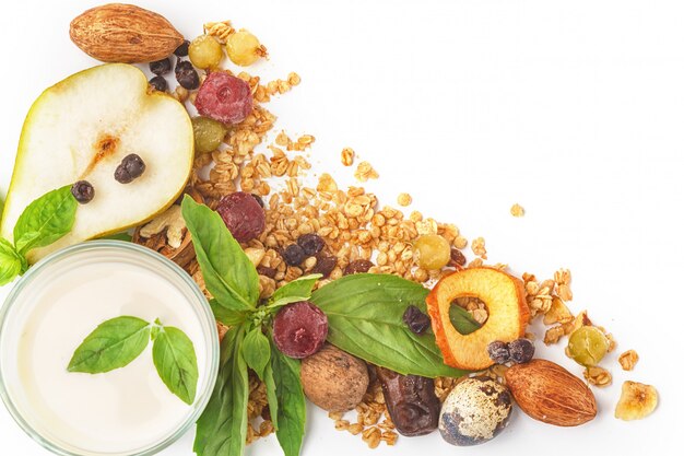 Un verre de lait et de muesli avec des fruits et des herbes sur un fond blanc