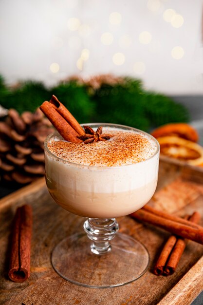 Un verre de lait de poule traditionnel de Noël sur une table, photo verticale avec espace de copie pour le texte. Boisson épicée à base d'œuf et de lait avec cannelle, cardamome. photo de haute qualité