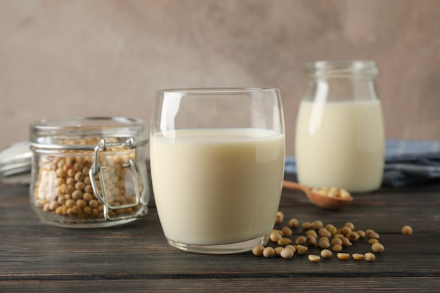 Verre de lait de soja, graines de soja sur cuillère, serviette sur table en bois