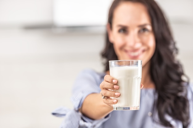 Verre de lait tenu par une femme vers une caméra.