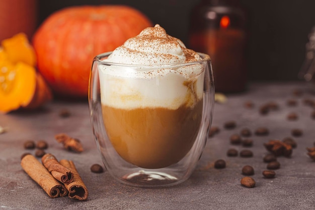 Un verre de latte de citrouille d'automne avec de la crème fouettée et des épices Café à la citrouille et à la cannelle sur fond sombre