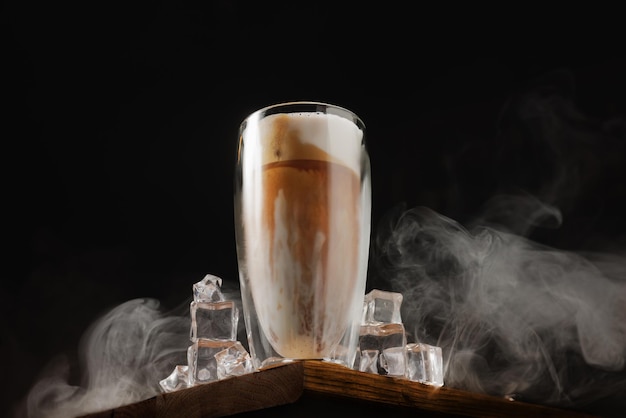 Verre de latte avec de la glace sur l'ancienne planche et fond sombre