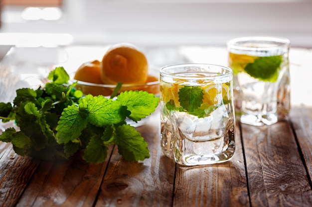 Verre de limonade au citron frais et menthe sur fond en bois