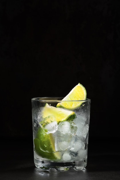 Verre de limonade au citron vert sur une table sombre, boissons estivales. Limonade maison au citron vert et glaçon. Idée boissons fraîches fraîches