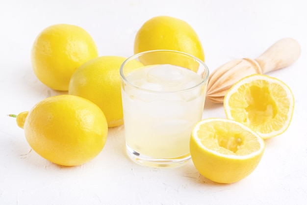 Verre de limonade fraîche savoureuse froide avec presse-agrumes en bois de citrons mûrs