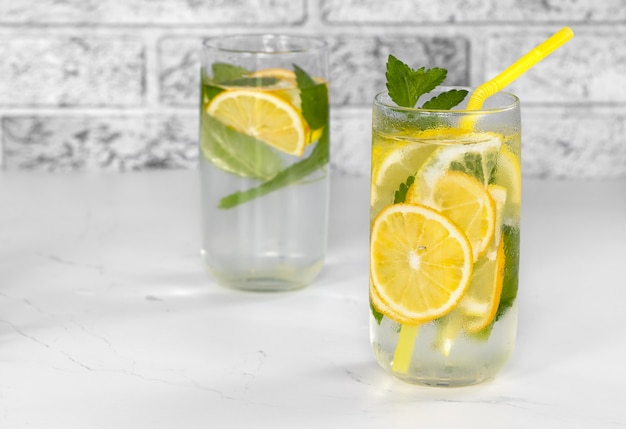 Un verre de limonade rafraîchissant sur une table blanche avec fond de mur de briques blanches