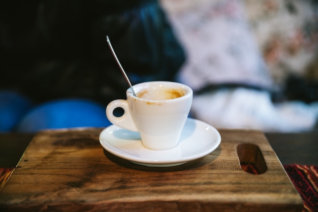 Verre à liqueur vide d&#39;arabica expresso avec une tache de café servi sur une planche de bois.