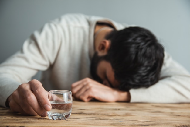 Verre à Main Homme Triste De Vodka Sur Le Bureau