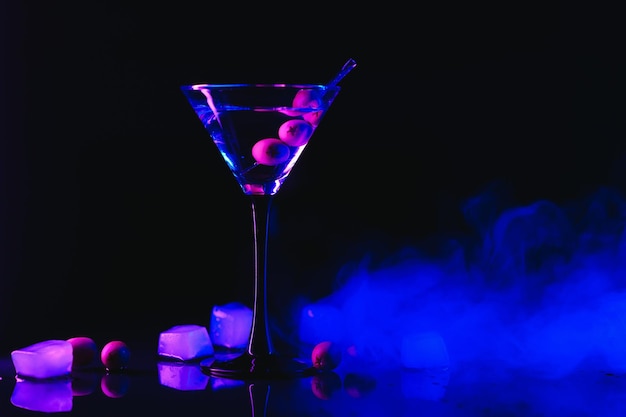 Verre à Martini et olives sur fond noir avec néons