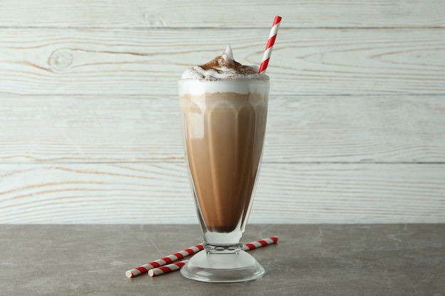 Verre de milk-shake au chocolat et pailles sur table grise