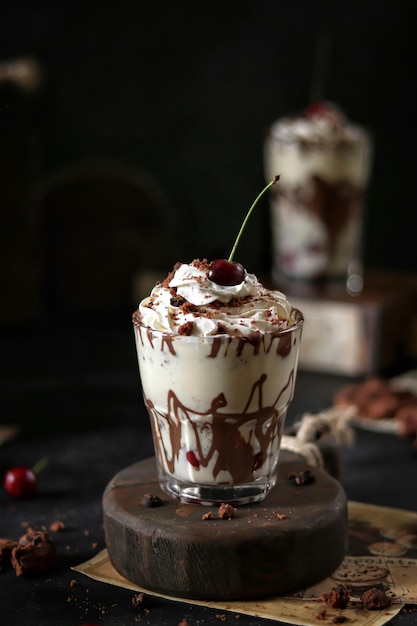 Un verre de milkshake au chocolat et aux cerises avec du sirop de chocolat et de la cerise sur le dessus.