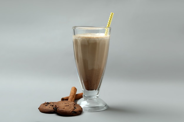 Verre de milkshake au chocolat, biscuits et cannelle sur fond gris