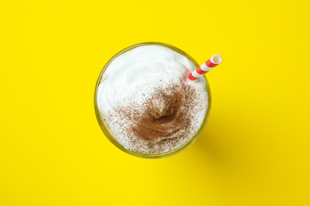 Verre de milkshake au chocolat avec de la paille sur mur jaune