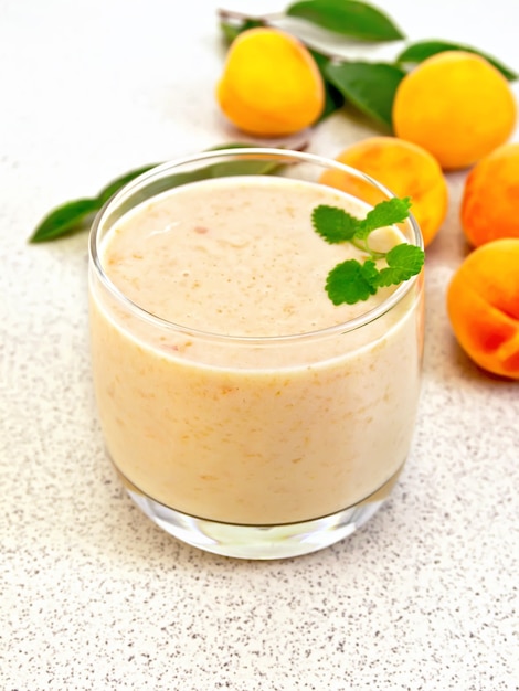 Un verre de milkshake aux abricots, menthe sur le fond de la table en pierre