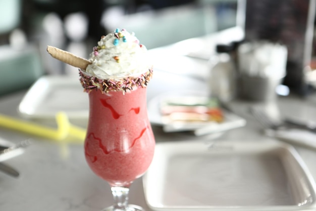 Verre de milkshake aux framboises avec crème fouettée et framboises fraîches