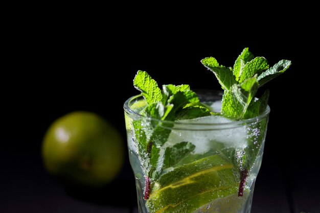 Un verre de mojito froid au citron vert et à la menthe sur un fond de bois noir Libre d'un cocktail rafraîchissant