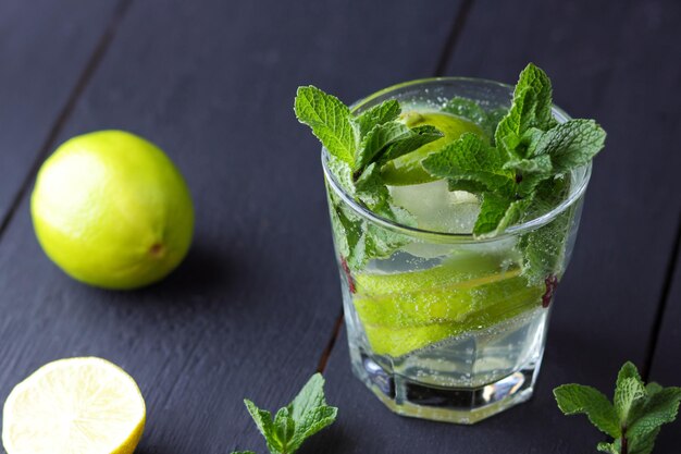 Un verre de mojito froid au citron vert et à la menthe sur un fond de bois noir Libre d'un cocktail rafraîchissant